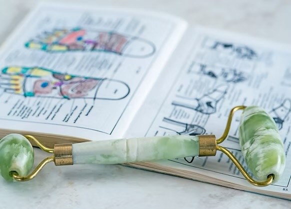 Carte des zones réflexes du pied dans un livre, avec un rouleau de massage en jade